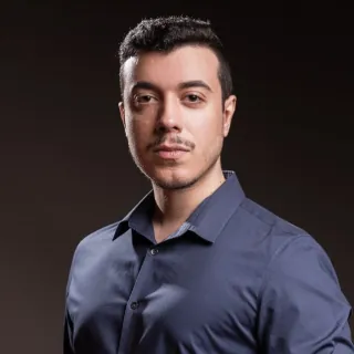Alexandre Polselli, de camisa azul, em retrato sobre fundo escuro